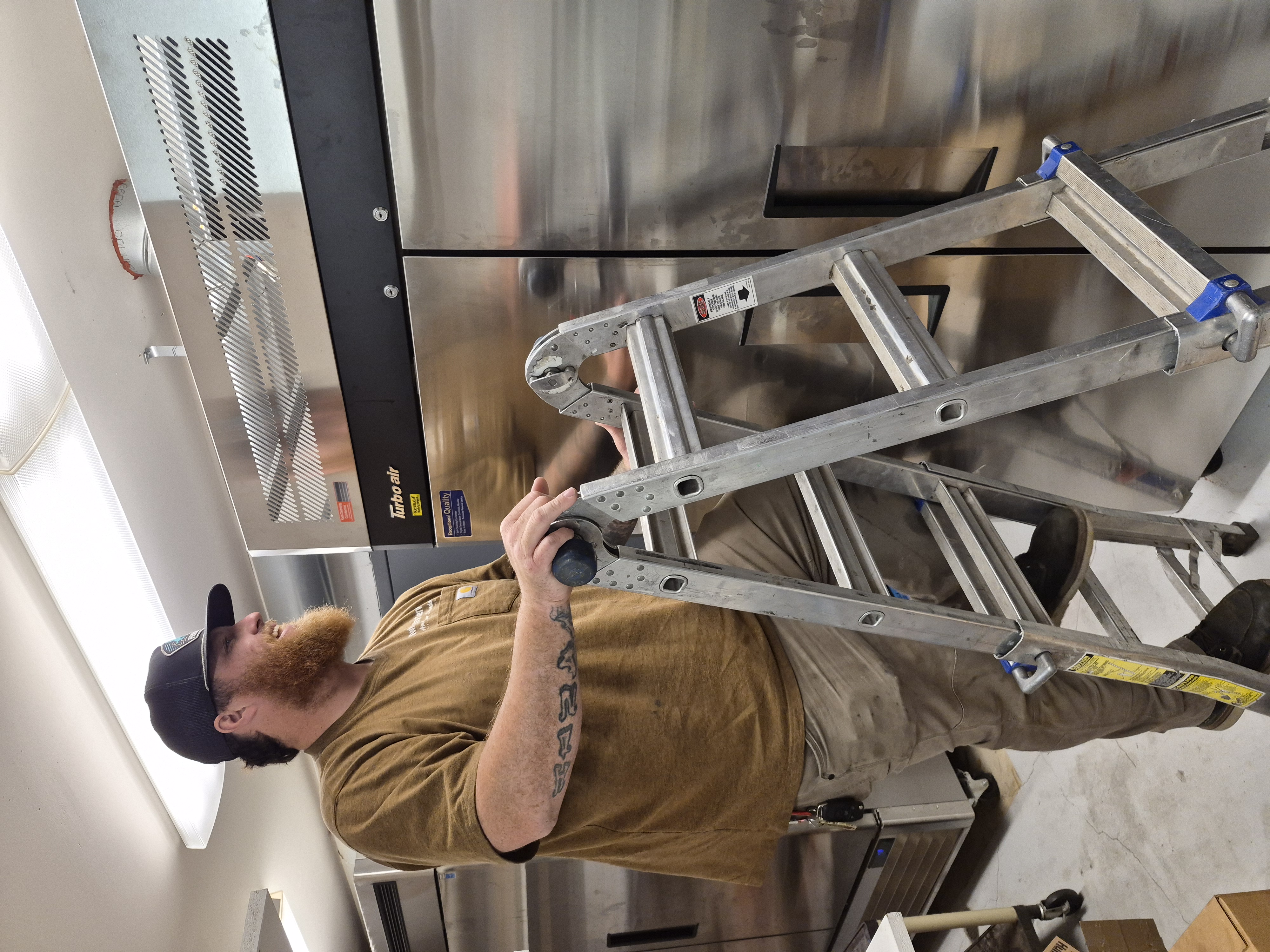 Twin City Service technician servicing commercial refrigeration in a restaurant kitchen